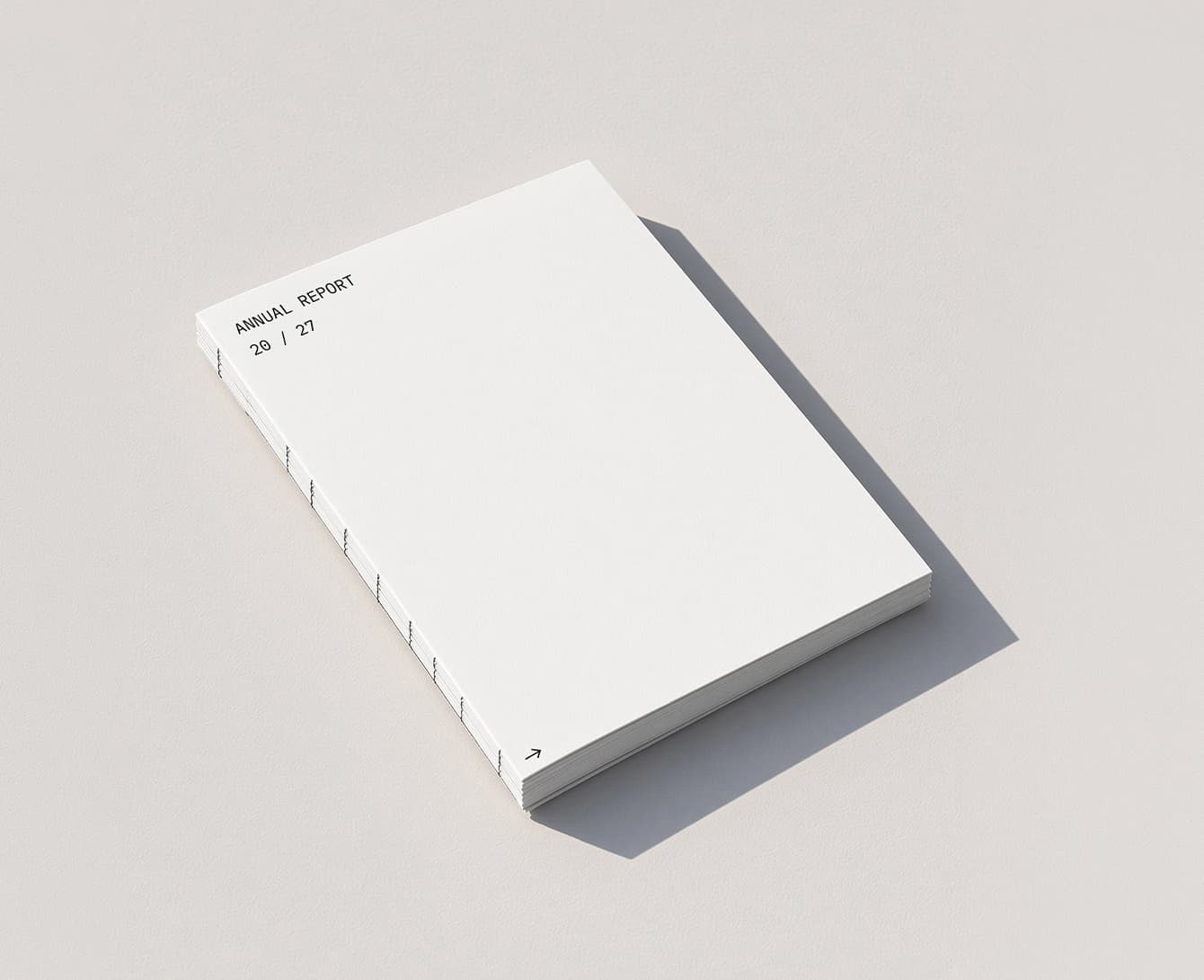 A section-stitched annual report lying closed on a pale ground, ANNUAL REPORT 20 / 27 set small in the corner.